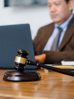 Crop concentrated Asian male judge in formal clothes sitting using modern netbook while working in law office